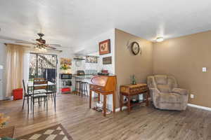 Sitting room with a ceiling fan, light wood-style floors, and a textured ceiling