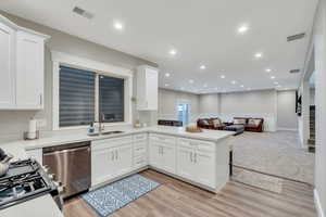 Kitchen with white cabinets, stainless steel appliances, open floor plan, recessed lighting, and a peninsula