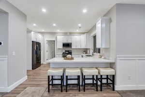 Downstairs Kitchen with a breakfast bar, white cabinetry, LVP flooring, and stainless steel appliances