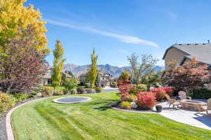 Fall  View of grassy yard featuring an outdoor fire pit, a patio area, and a mountain view