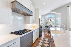 Kitchen featuring custom cabinets, quartz  counters, stainless steel appliances, and hardwood flooring