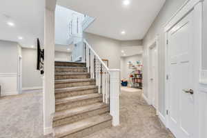 Stairs with carpet floors and recessed lighting