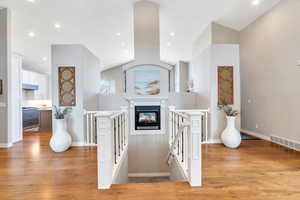 Hallway featuring an upstairs landing, light wood-style flooring, recessed lighting, and lofted ceiling