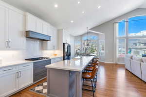 Kitchen featuring custom  cabinetry, a breakfast bar, quart countertops, and backsplash