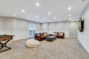 Downstairs family room featuring wainscoting, recessed lighting, carpet, and walk-out