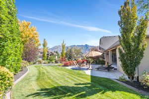 View of green lawn featuring a patio, a mountain view, and a residential view