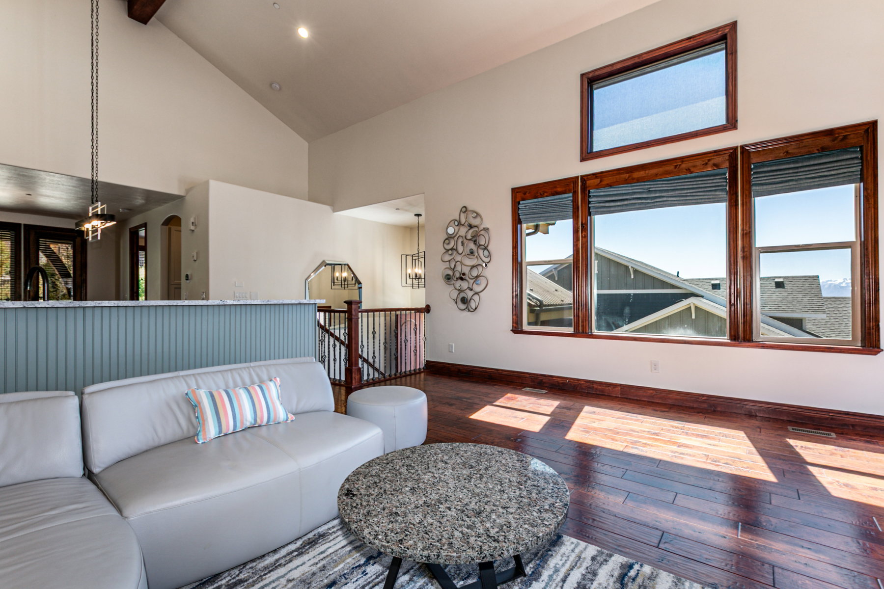 Spacious living area featuring high vaulted ceilings, rich wood-finish flooring, and multiple large windows with dark wood trim