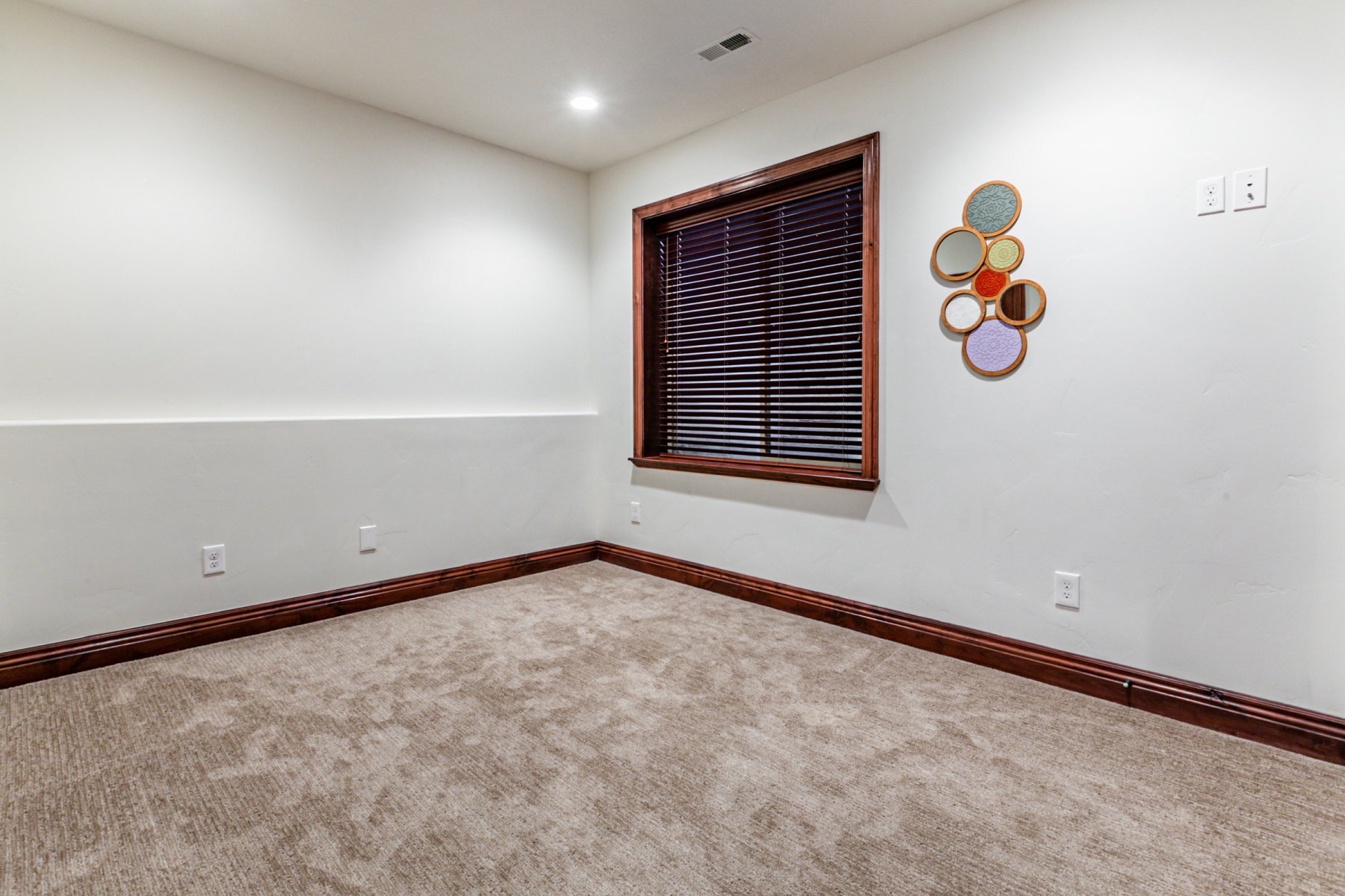 Room with light beige patterned carpeting, white walls, and dark wood-finish baseboards