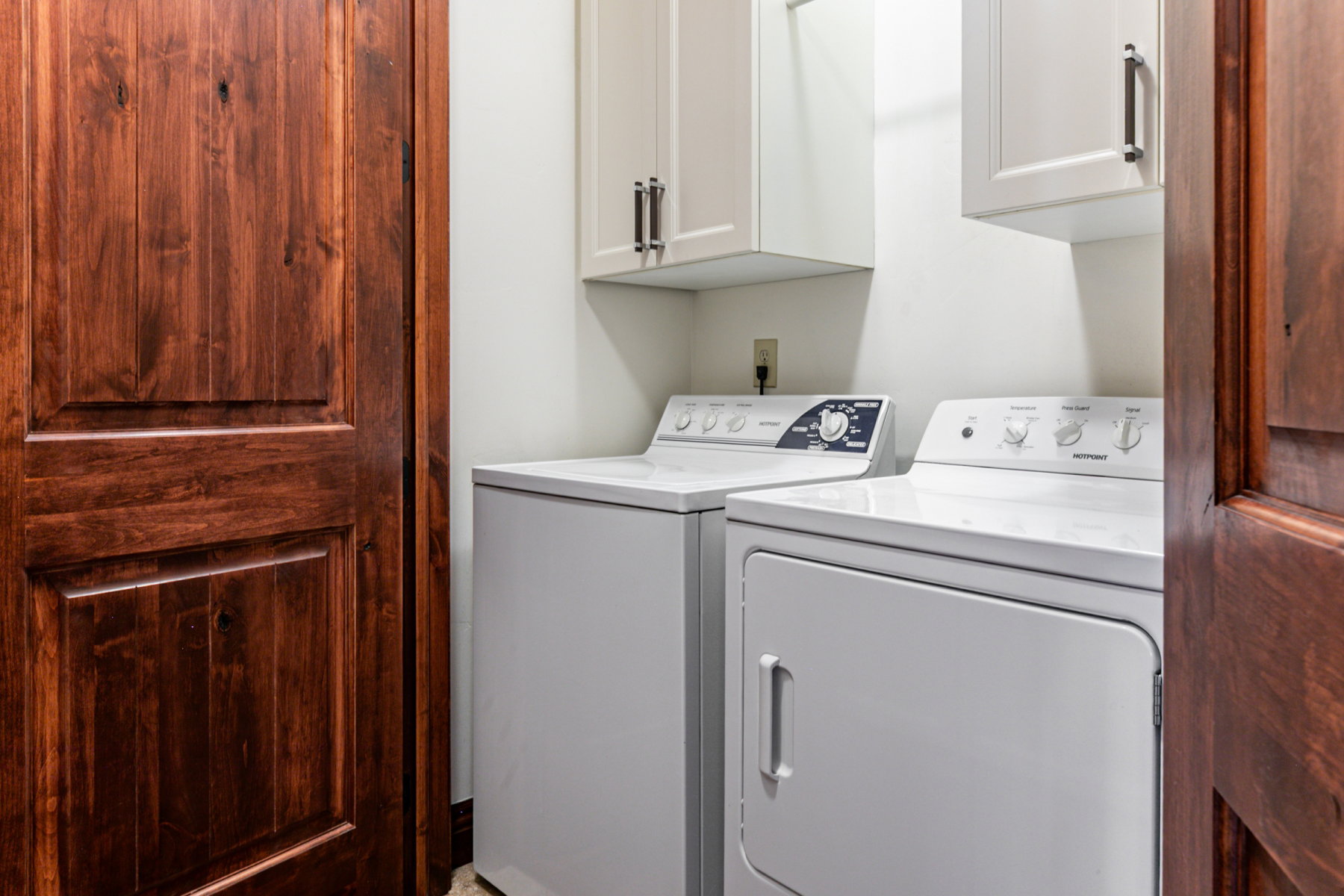 Laundry area featuring white cabinetry with dark hardware and paneled wood doors