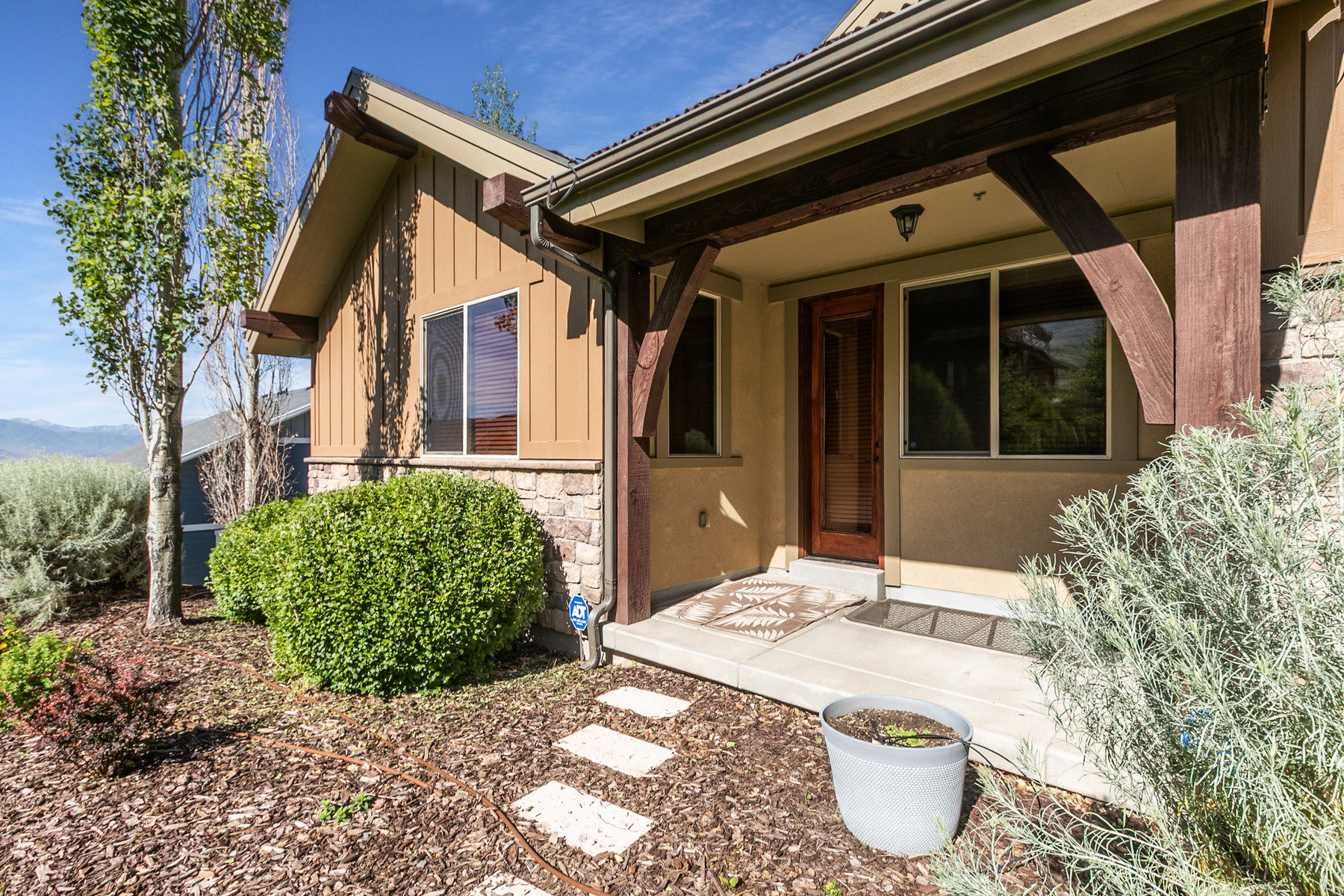 Craftsman-style exterior featuring a covered porch entry with substantial wood beams, stone accents, and a paneled wood-finish door