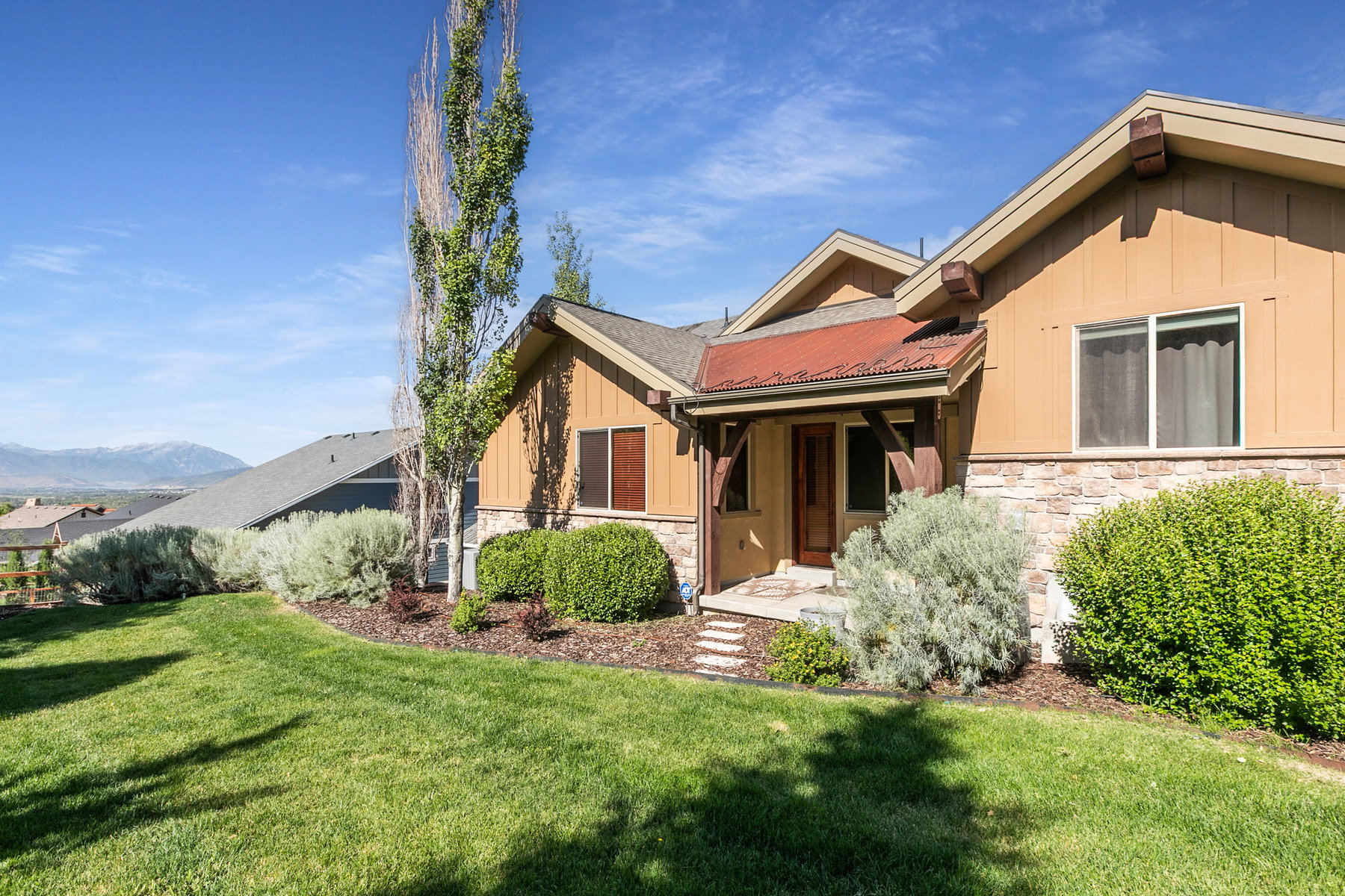 Craftsman-style exterior featuring a covered entry, corrugated metal awning, stone accents, and wood-finish siding