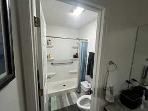 Bathroom featuring a stall shower and dark wood-style floors