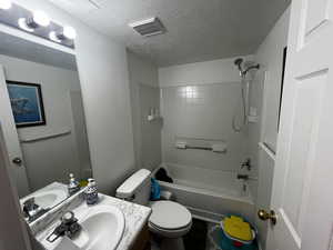 Full bath with vanity, a textured ceiling, and  shower combination