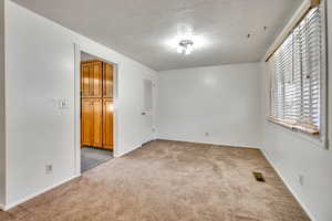 Spare room with a textured ceiling and light carpet