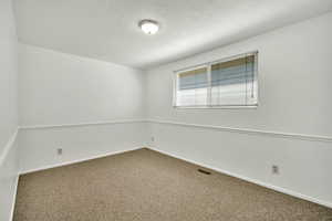 Spare room featuring dark carpet and a textured ceiling