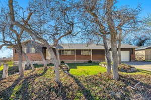Single story home with brick siding, an attached garage, and concrete driveway
