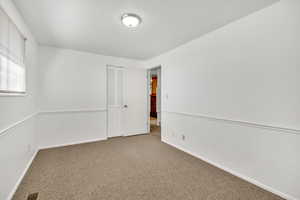Empty room featuring dark colored carpet and baseboards