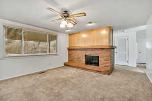 Unfurnished living room featuring ceiling fan, carpet, and a fireplace