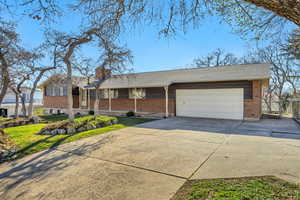 Single story home with concrete driveway, brick siding, a chimney, an attached garage, and roof with shingles