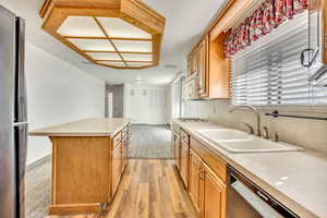 Kitchen featuring light countertops, stainless steel appliances, light wood-style flooring, and wood finish cabinetry