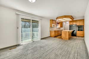Kitchen with light countertops, a kitchen island, black appliances, and wood finish cabinetry