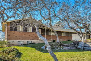 View of front of property featuring brick siding, a front lawn, and an attached garage