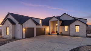 Modern farmhouse style home with board and batten siding, stone siding, and driveway