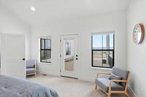 Primary Bedroom featuring multiple windows, light colored carpet, and lofted ceiling