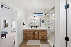 Primary bathroom with vanity, a marble finish shower, ceiling fan, and light tile patterned flooring