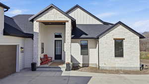 View of front of home with board and batten siding, stone siding, and a shingled roof