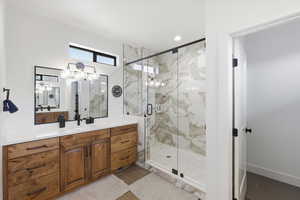 Primary Bathroom with a marble finish shower, vanity, light tile patterned floors, and recessed lighting
