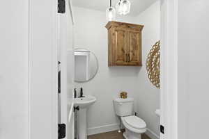 Half bathroom featuring toilet and dark tile patterned flooring