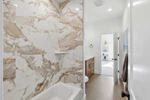 Full bathroom jack and jill with vanity, shower / washtub combination, and light tile patterned flooring