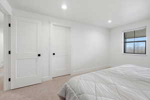 Bedroom with light colored carpet and recessed lighting