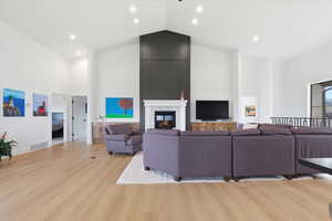 Living room with light wood-style flooring, recessed lighting, vaulted ceiling, and a tiled fireplace