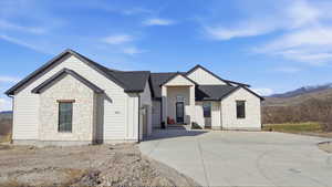 View of front of property with stone siding, a mountain view, a garage, a shingled roof, and driveway