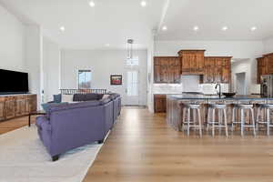 Kitchen with open floor plan, a kitchen bar, light wood-type flooring, a large island, and high end refrigerator