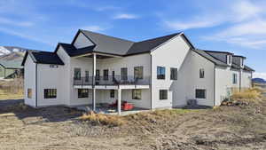 Rear view of property featuring a patio area, a mountain view, a shingled roof, and a balcony