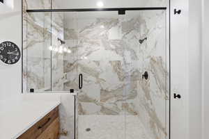 Full bathroom featuring a marble finish shower and vanity