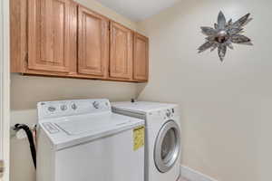 Laundry room featuring independent washer and dryer and cabinet space