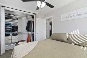 Carpeted bedroom with a closet and ceiling fan