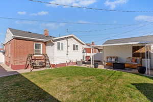 Back of house featuring a patio, an outdoor hangout area, brick siding, and a chimney