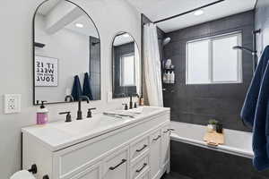 Bathroom featuring double vanity and tiled shower / bath combo