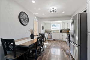 Dining space with a textured wall, dark wood finished floors, and recessed lighting
