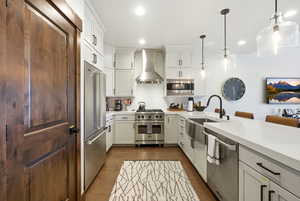 Kitchen featuring white cabinets, high end appliances, a breakfast bar, decorative backsplash, and dark wood-type flooring