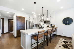 Kitchen with a kitchen bar, white cabinets, dark wood finished floors, stainless steel appliances, and a peninsula
