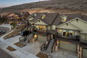 View of front of house with an attached garage, a deck, driveway, board and batten siding, and stone siding
