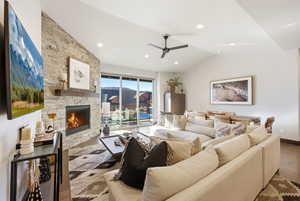 Living room with ceiling fan, a fireplace, wood finished floors, and vaulted ceiling