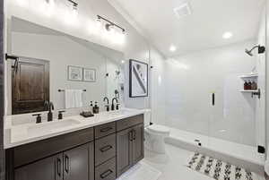 Bathroom with double vanity, a stall shower, recessed lighting, and vaulted ceiling