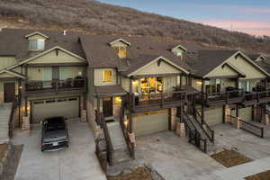Craftsman house featuring an attached garage, concrete driveway, stone siding, roof with shingles, and board and batten siding